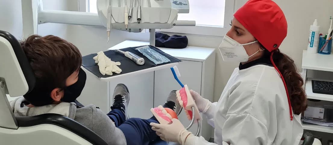 Una higienista de Mesena Dental enseñando a cepillarse a un niño en el gabinete